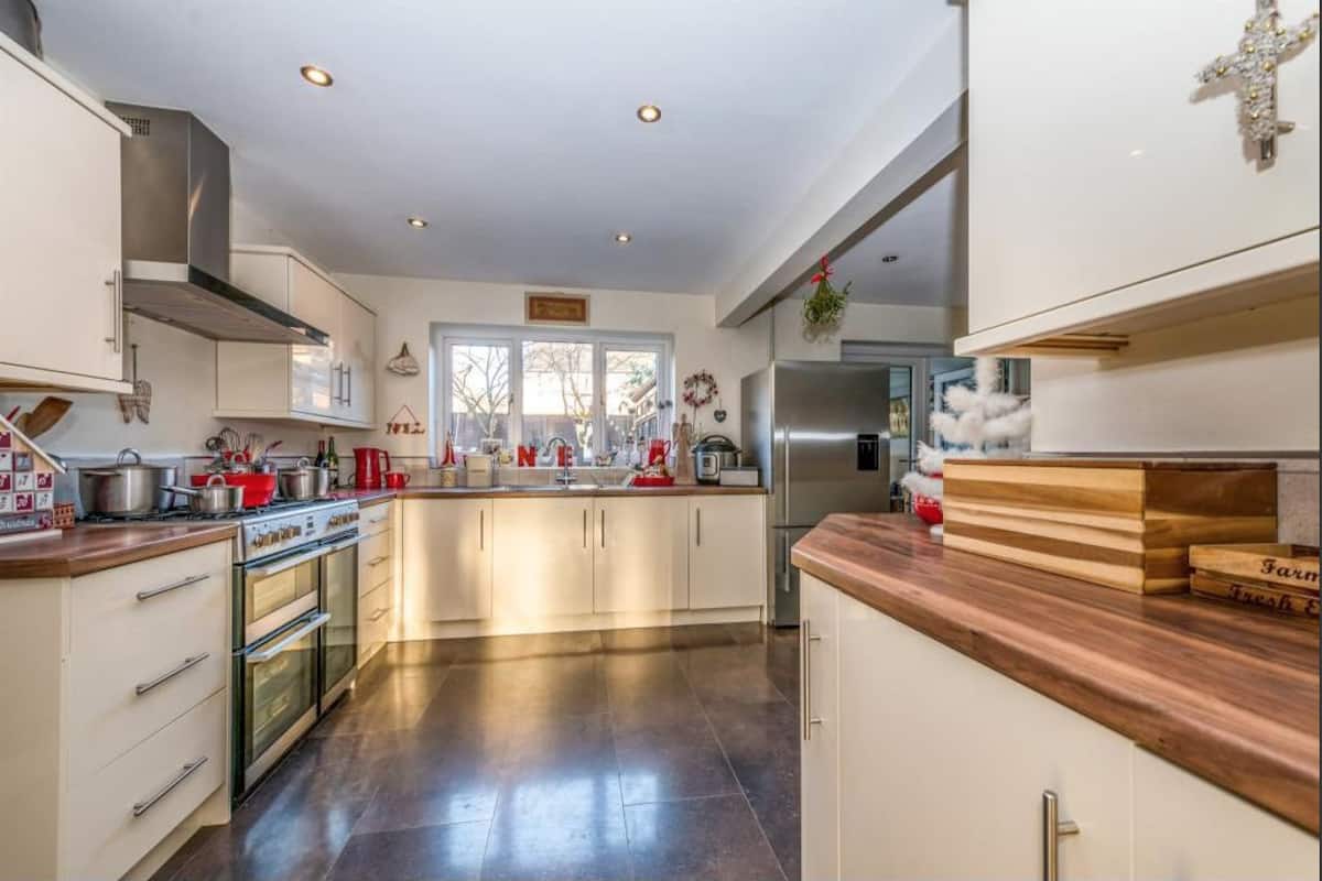A modern kitchen with white cabinets, stainless steel appliances, and a wooden countertop.
