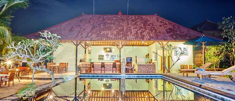 A hotel with a swimming pool, wooden deck, and outdoor seating area.