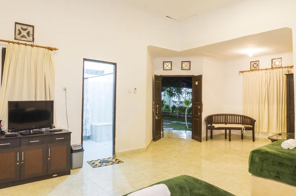 Habitación de hotel con televisión, un banco, una cama y vistas al exterior.