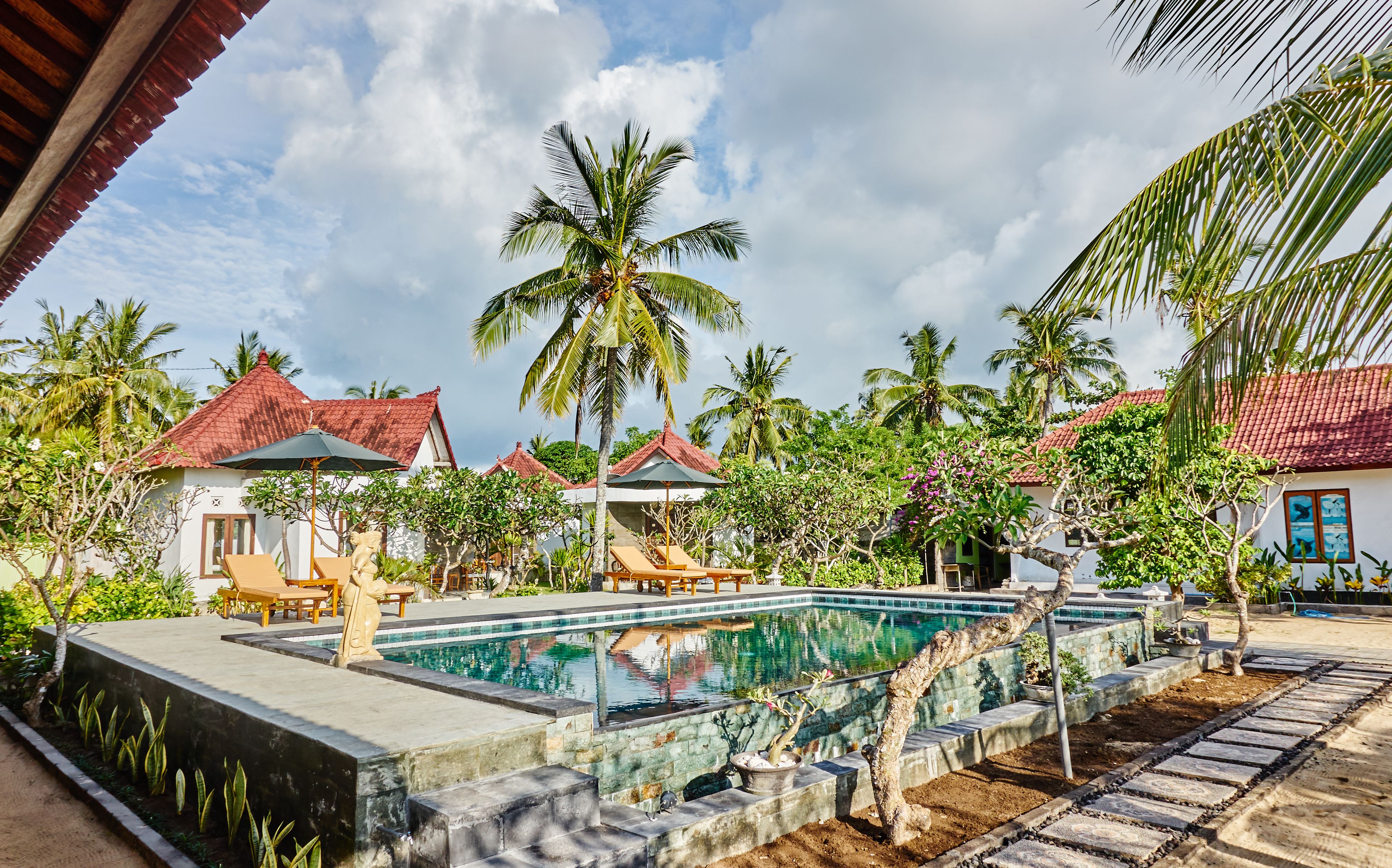 A pool area with lounge chairs, a small pool, and palm trees.