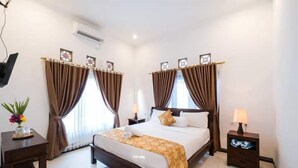 A hotel room with a large bed, two bedside tables, a desk, and a chair. - Scoobydoo Bungalow (Lembongan Island)