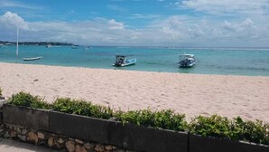 A beach with a sandy shore and a few boats in the water. - Scoobydoo Bungalow (Lembongan Island)