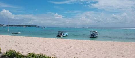A beach with a sandy shore and a few boats in the water.
