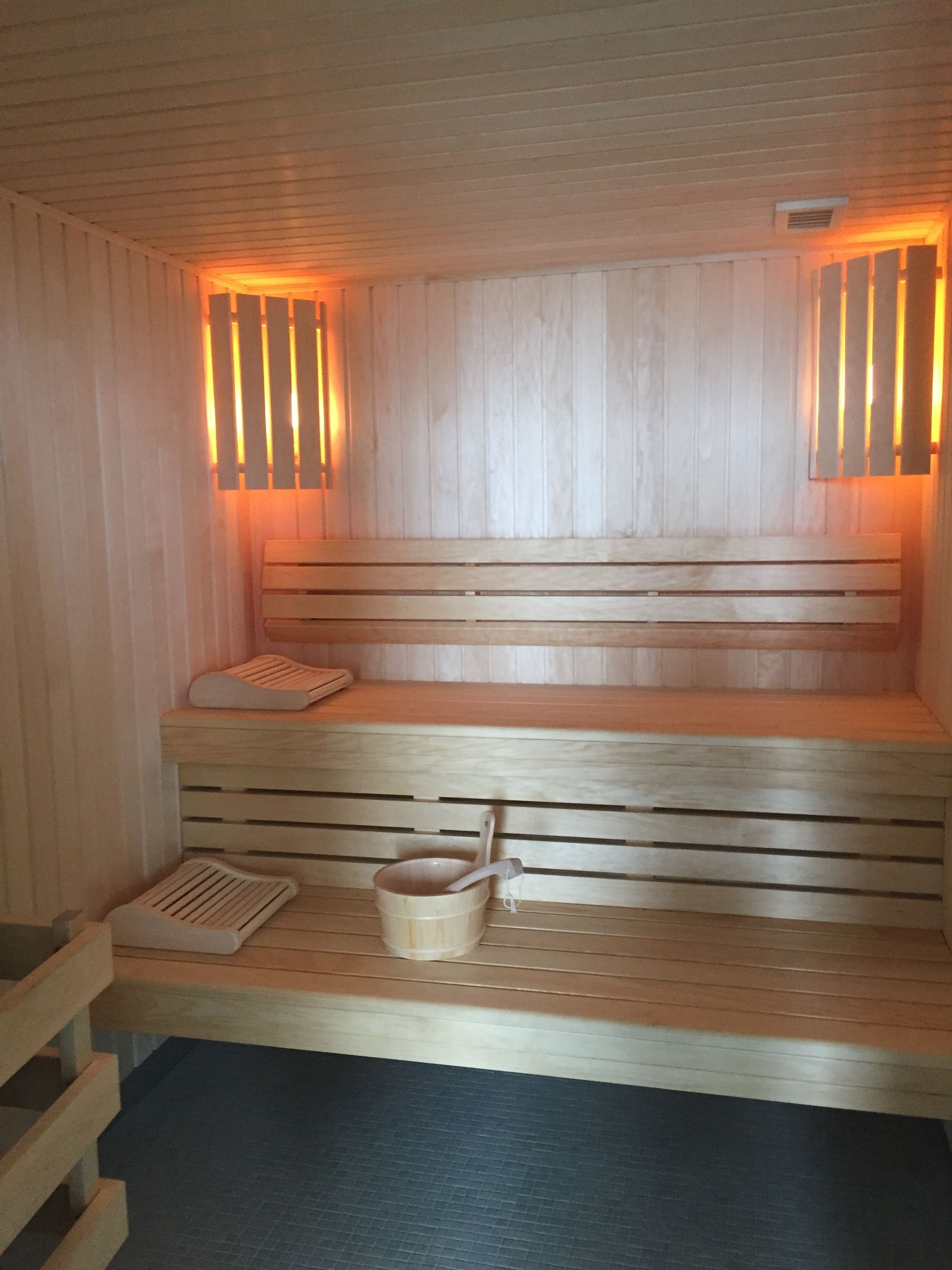 Un sauna en bois avec des bancs et un seau.