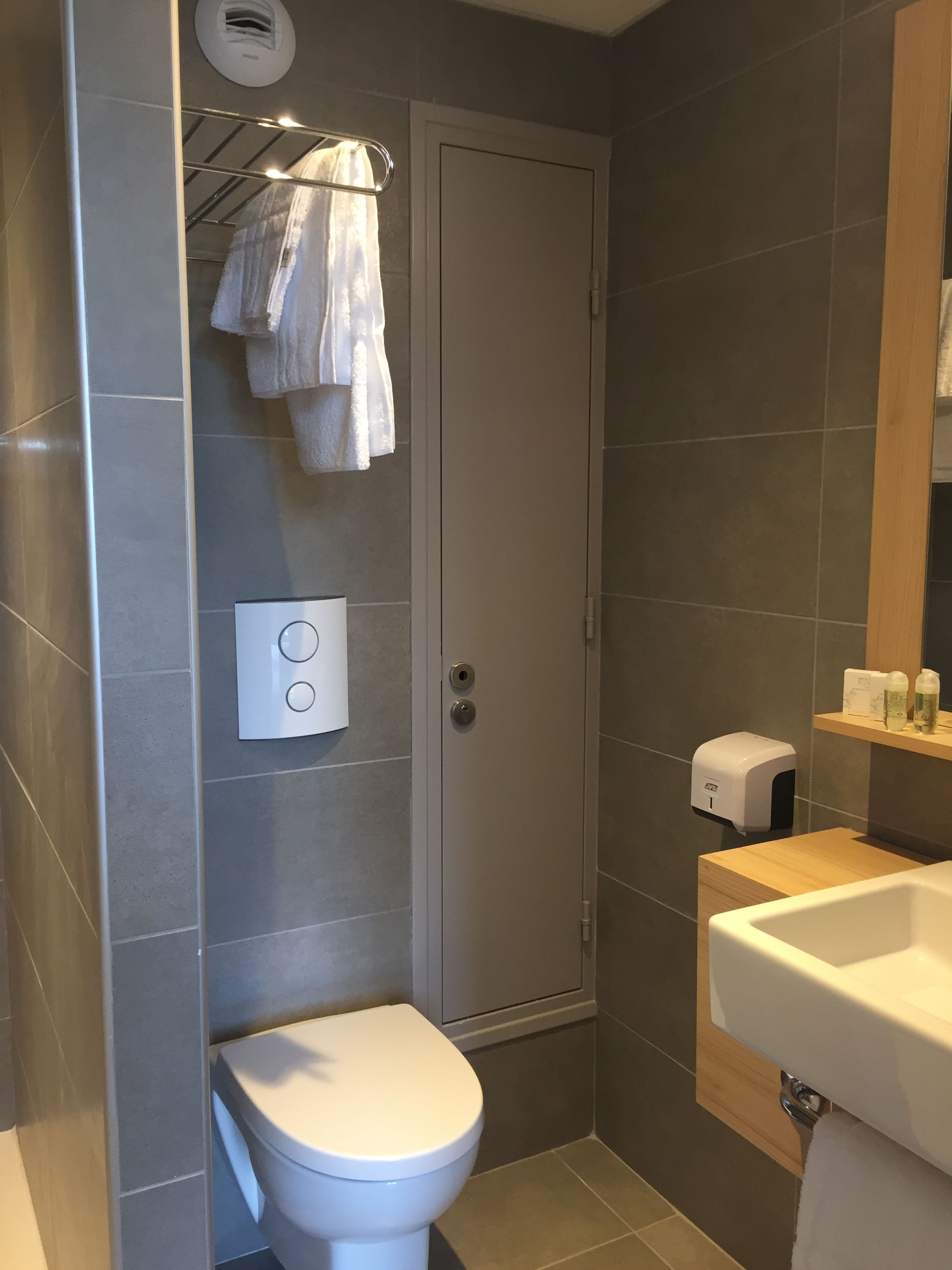 A modern bathroom with a toilet, a shower, and a sink.
