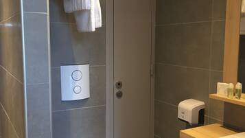 A modern bathroom with a toilet, a shower, and a sink.