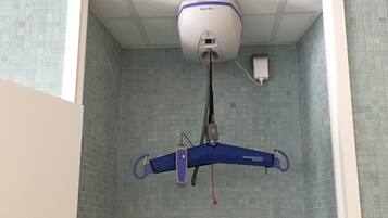 Un dispositivo fijado al techo, posiblemente un monitor de seguridad o calidad del aire, en una habitación con paredes de azulejos y techo blanco.