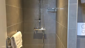 A modern shower with a handheld showerhead and a wall-mounted control panel.