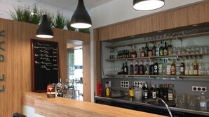 Eine Barbereich mit Holzböden, voll mit verschiedenen Flaschen und Gläsern, eine Kreidetafel mit der Speisekarte und zwei Pendelleuchten.