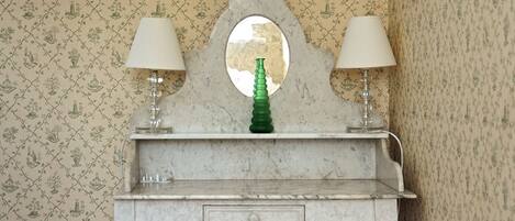 A vanity with a mirror, two lamps, and a green bottle.