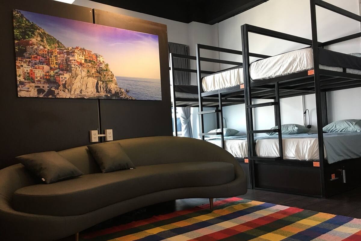 Een slaapkamer met een stapelbed, een bank en een kleurrijk vloerkleed.