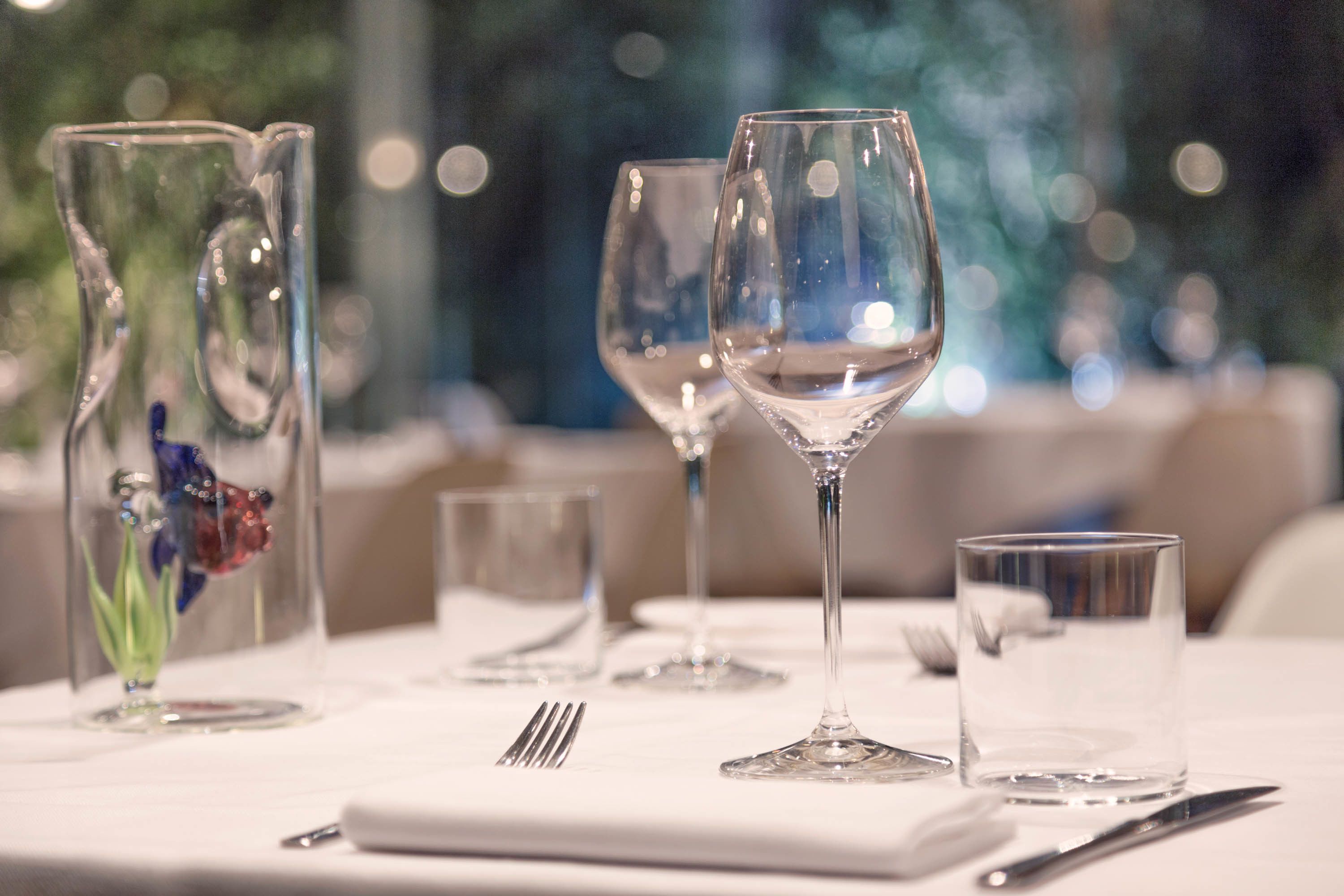 A dining table with wine glasses, a water glass, and cutlery.