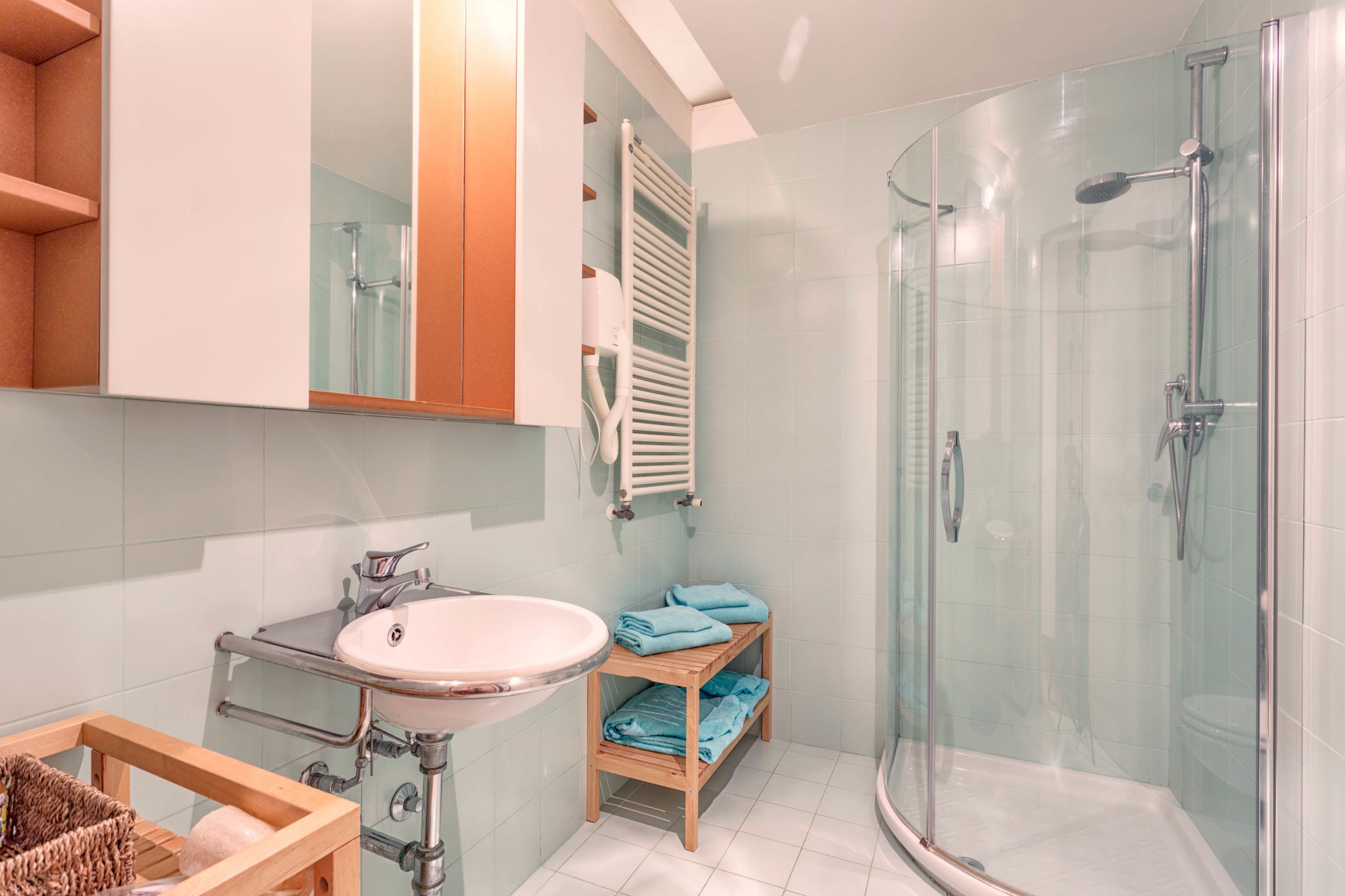 Une salle de bain moderne avec une douche à parois de verre, un lavabo avec un meuble-vasque en bois et un porte-serviettes.