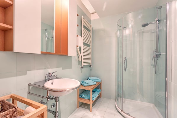 A modern bathroom with a glass-enclosed shower, a sink with a wooden vanity, and a towel rack. - Casale del Mare (Rosignano Marittimo)