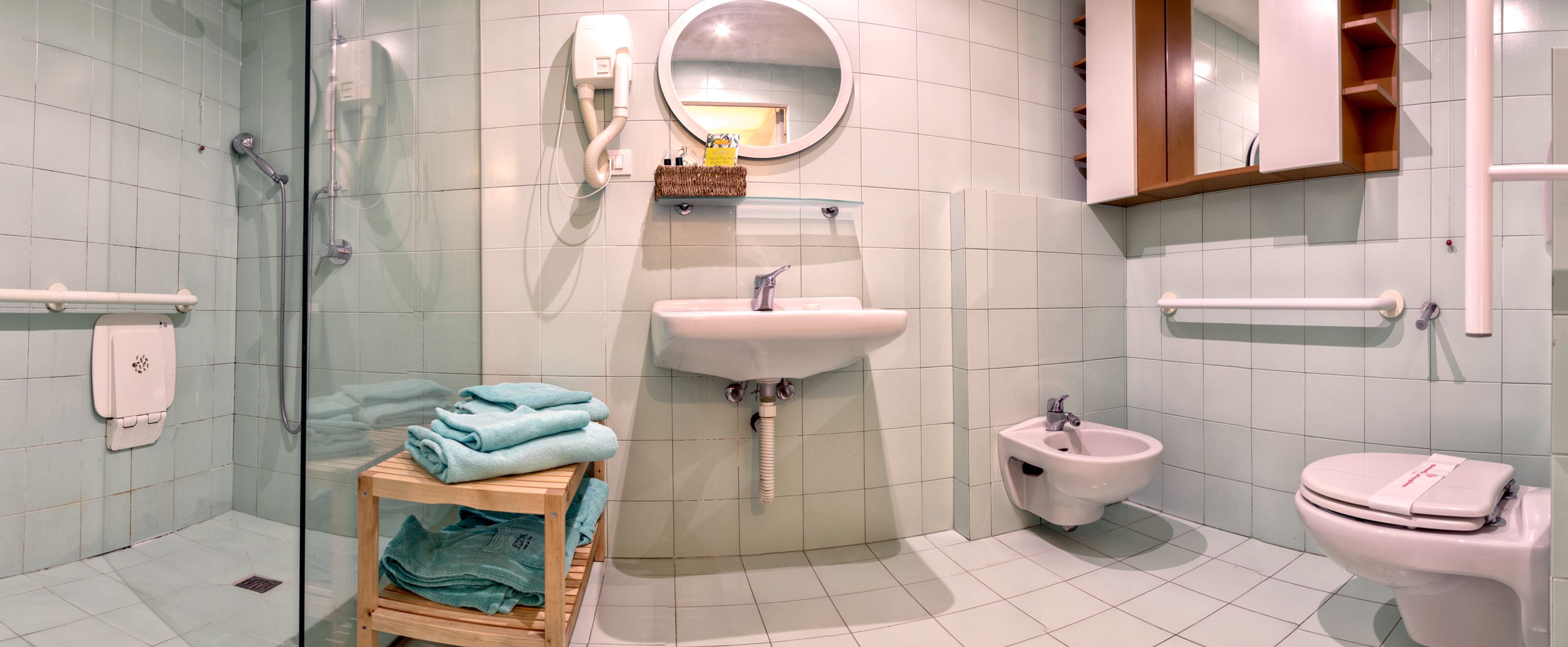Ein modernes Badezimmer mit Duschkabine aus Glas, Waschbecken mit Spiegel darüber, einem Bidet und einer Toilette.