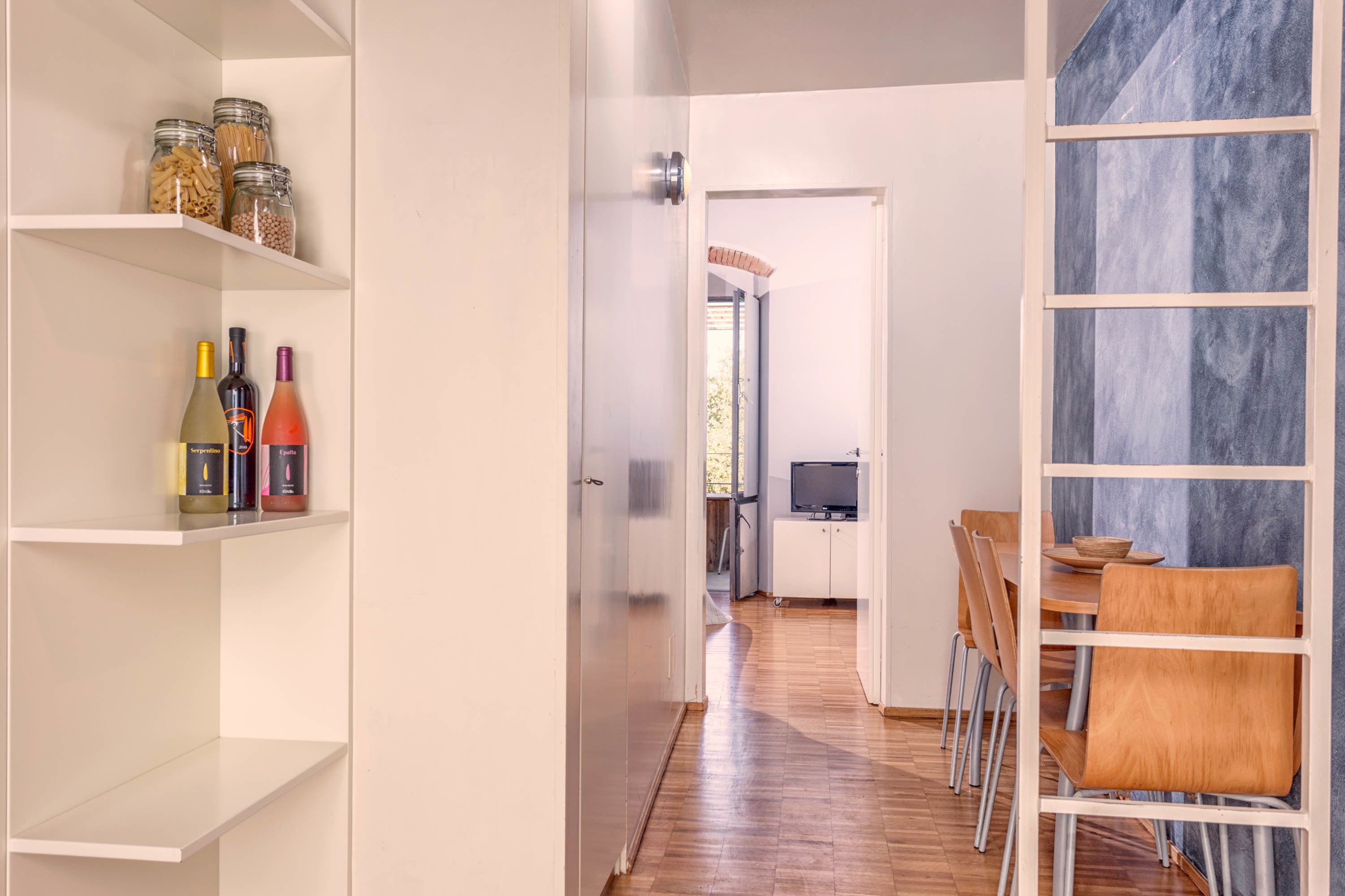 Una cocina moderna con armarios blancos, una mesa de comedor de madera y un televisor.