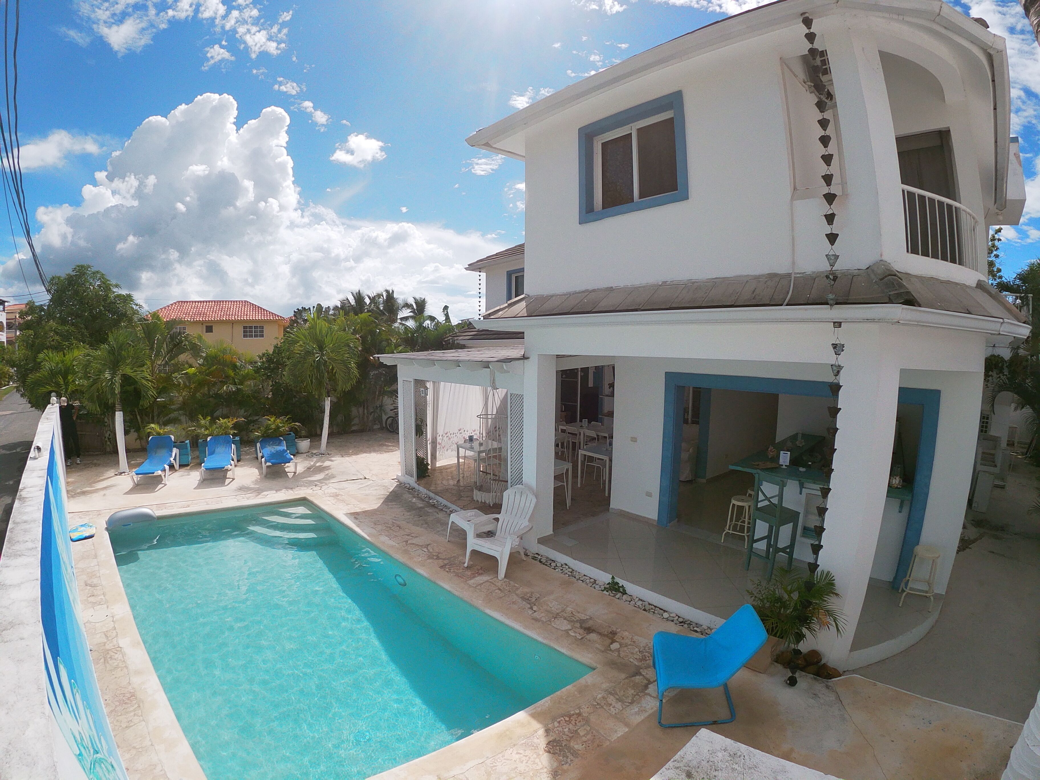 Ein zweistöckiges Haus mit Swimmingpool, Sitzgelegenheiten im Freien und einer überdachten Terrasse.