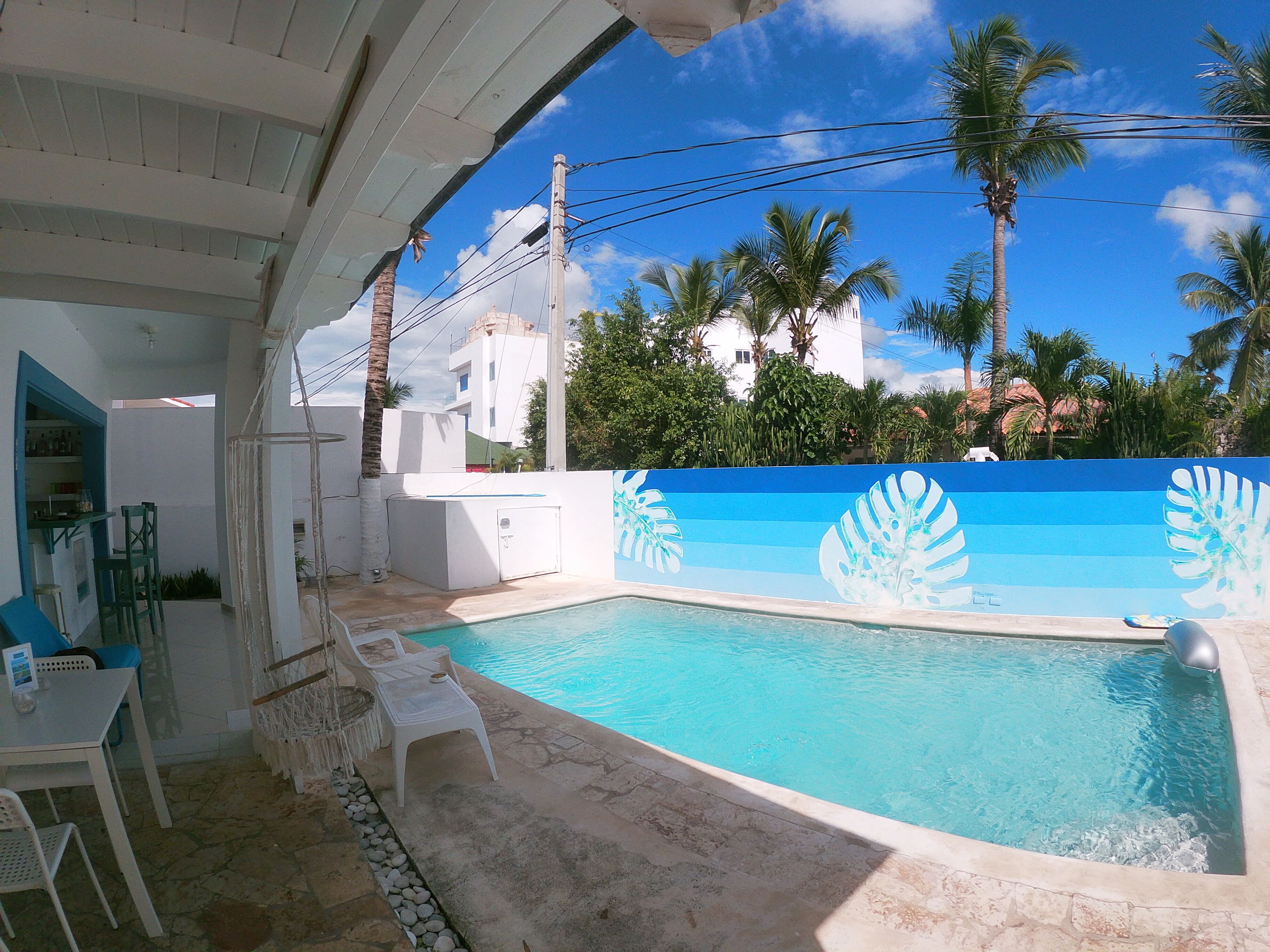 A pool area with a blue and white mural, a white building, and palm trees.