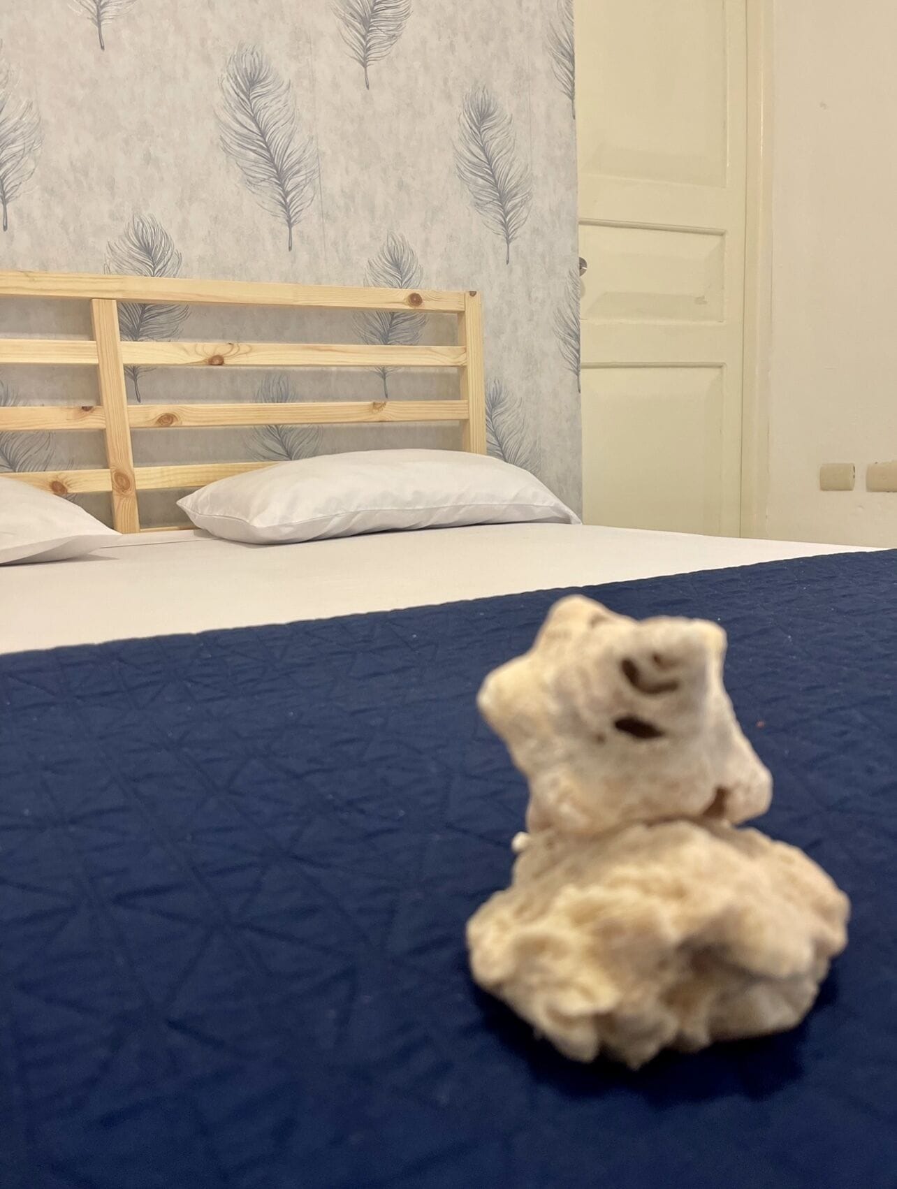 Una cama con una colcha azul y una almohada blanca.