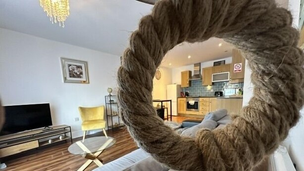 Una sala de estar con un sofá, un televisor y una cocina al fondo.