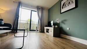 Una sala de estar moderna con una televisión de pantalla plana, una mesa de centro y un sofá.