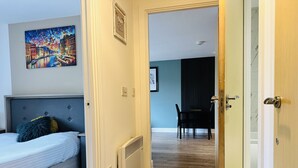 Una habitación de hotel con cama, radiador, mesa de comedor con sillas y un cuadro en la pared.
