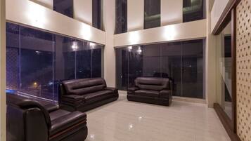 A spacious living area with large windows and a high ceiling.