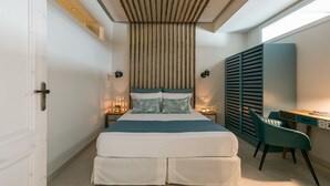 Un dormitorio con cama, mesitas de noche, escritorio y silla.
