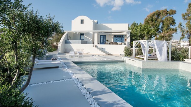 Un edificio moderno blanco con piscina y mobiliario exterior.