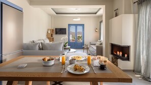 Un comedor con una mesa de madera dispuesta para el desayuno, un sofá y una chimenea.