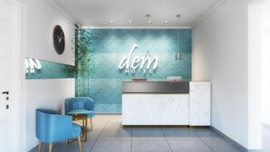 Un área de recepción de hotel moderna, con una pared de diseño azul en patrón de espiga, un mostrador de recepción y dos sillones azules.