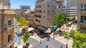 Un edificio de varios pisos con balcones, un patio central y árboles circundantes.
