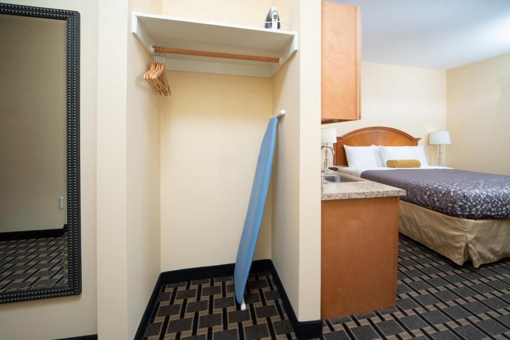 Una habitación de hotel con una cama, una mesita de noche, un espejo y un perchero para toallas.
