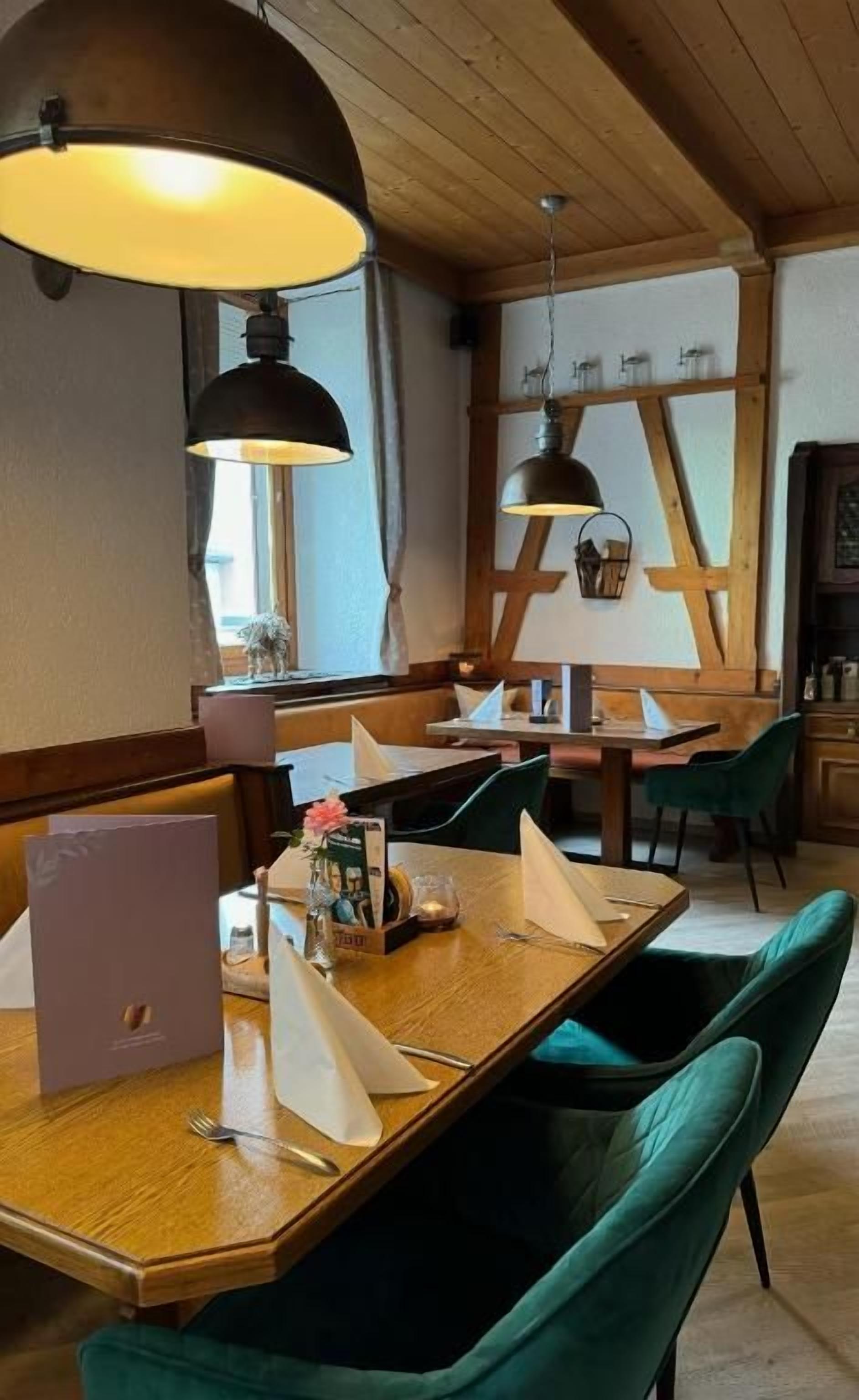 Ravintolassa on puupöydät ja -tuolit, pöydällä on kannettava tietokone ja katosta roikkuu riippuvalaisimia.