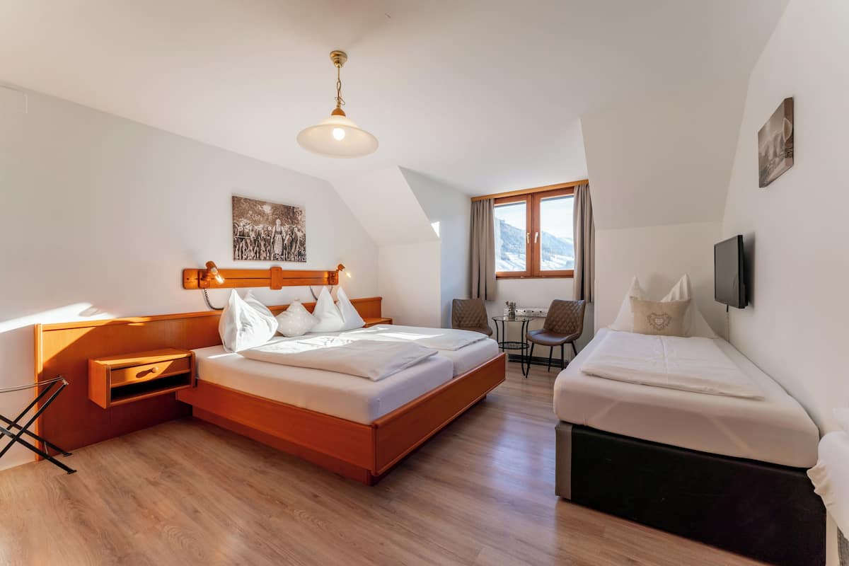 A modern bedroom with a large bed, a smaller bed, a desk, and a chair.