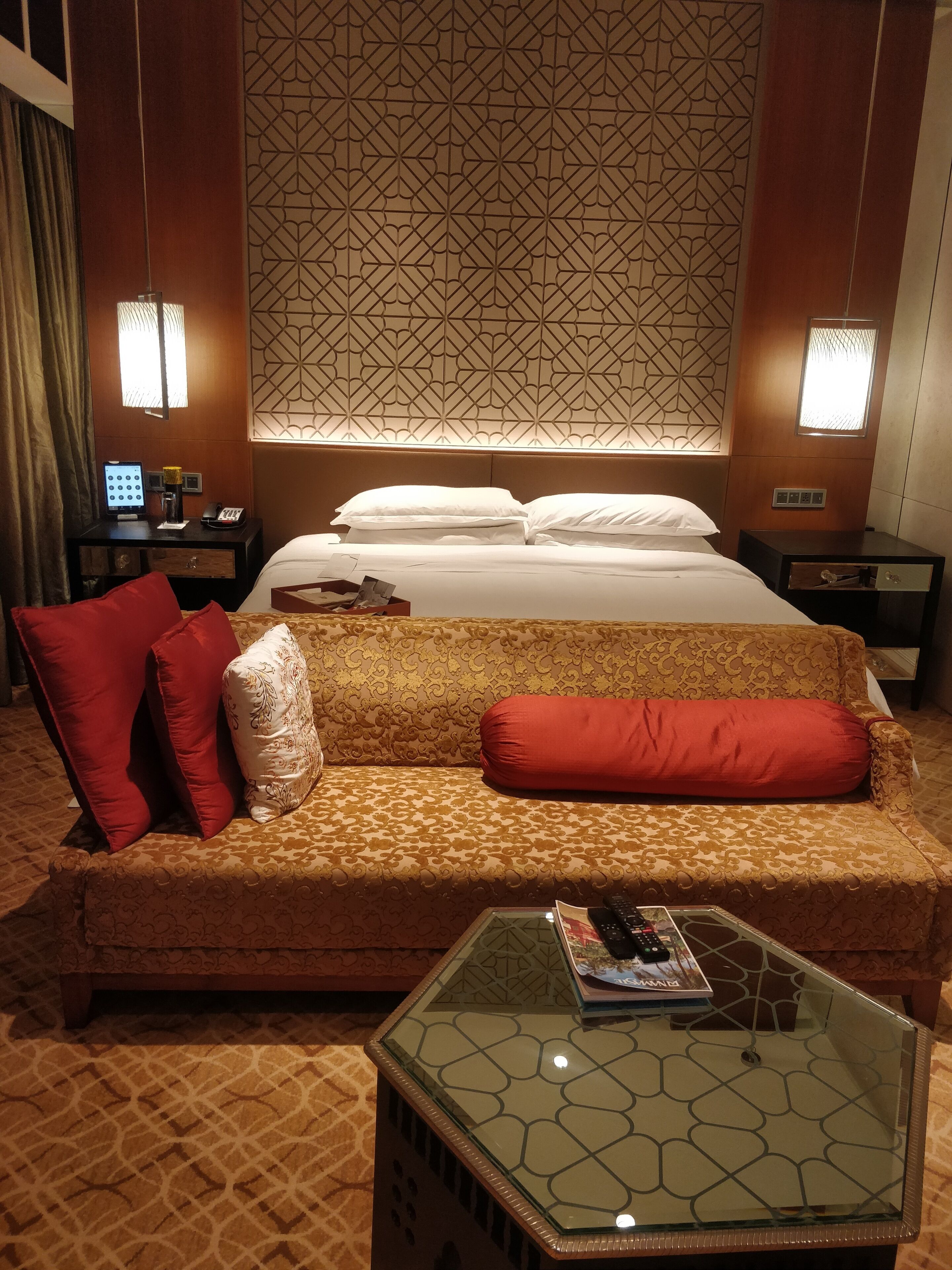 Una habitación de hotel con una cama, un sofá, una mesa de centro de vidrio y una pared con diseño.