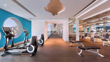 Un gimnasio moderno con cintas de correr, elípticas y bancos de pesas.