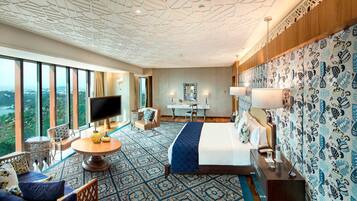 A hotel room with a large bed, a TV, a desk, and a view of the city.