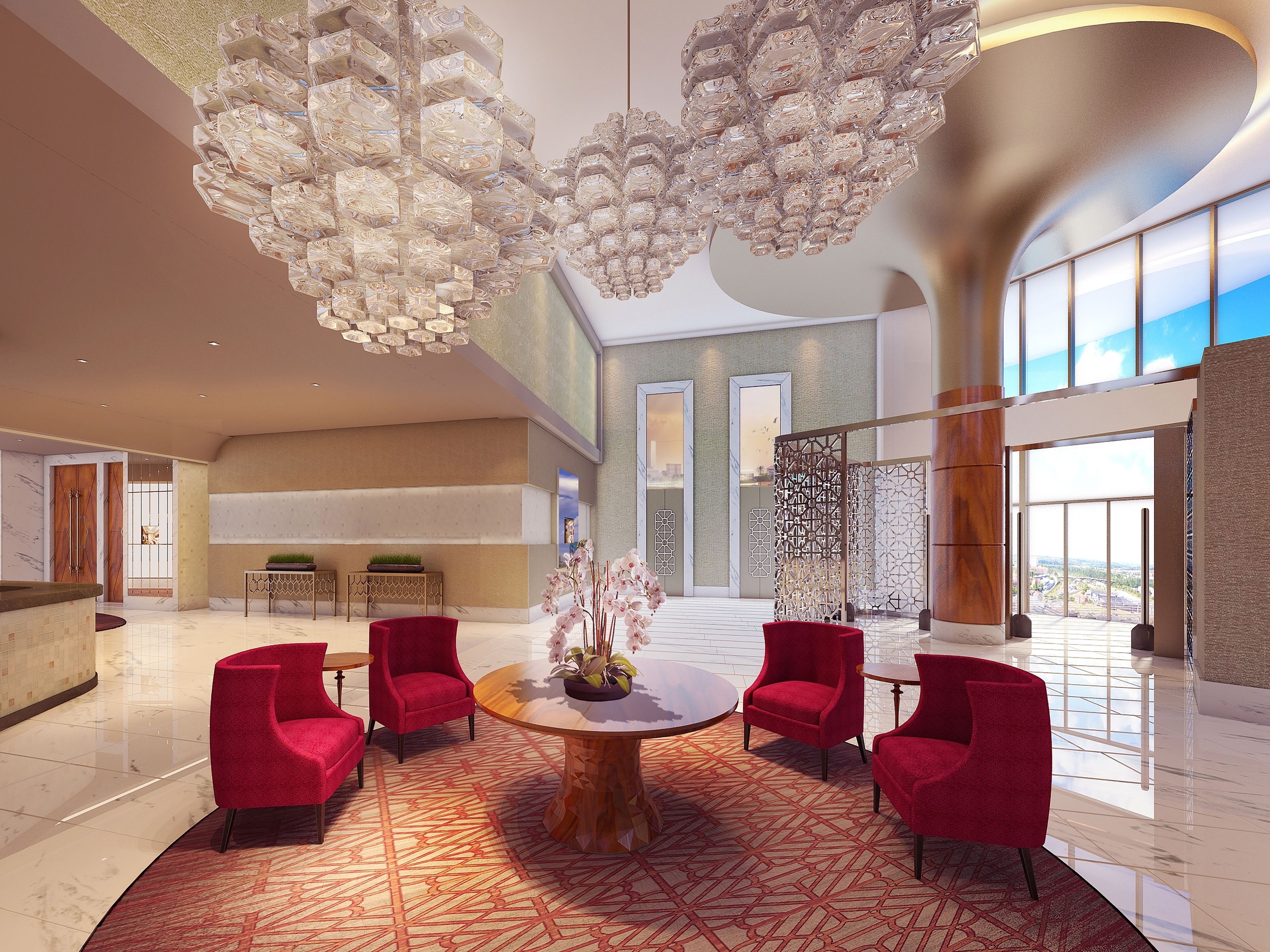 A spacious lobby with a central round table, red chairs, and a modern chandelier.