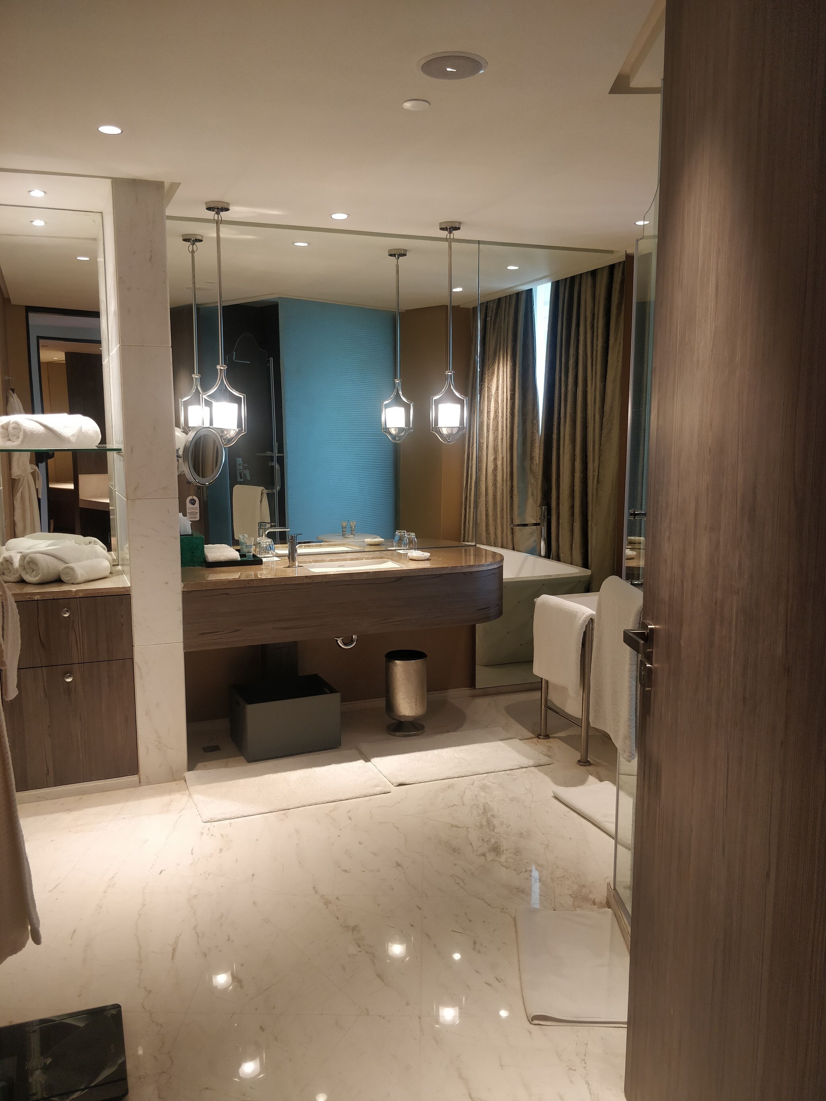 Un baño moderno con un espejo grande, un lavamanos y un perchero para toallas.