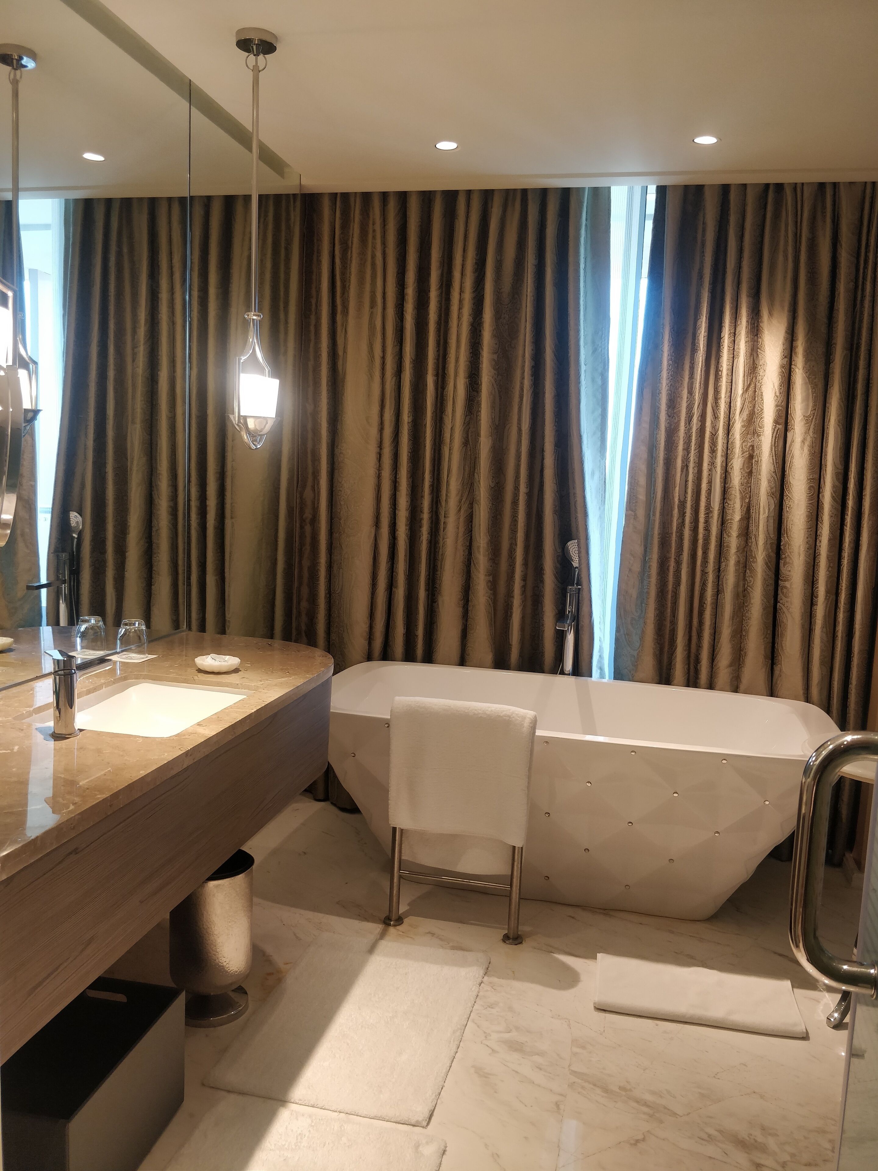 A modern bathroom with a freestanding bathtub, a large mirror, and a vanity with a sink and towel rack.