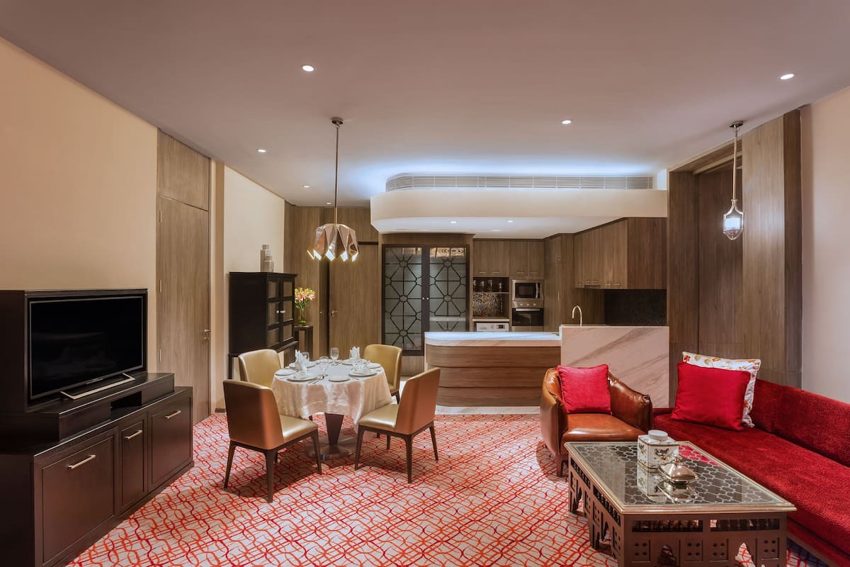 Ett modernt hotellrum med en matplats, en TV och en röd soffa.