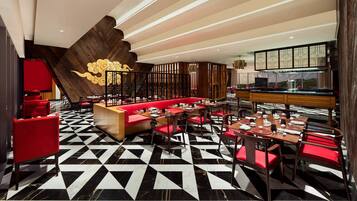 A restaurant with a black and white checkered floor, red seating, and a wooden accent wall with a golden design.