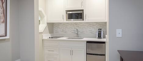 A modern kitchen with white cabinetry, a microwave, a coffee maker, and a dishwasher.