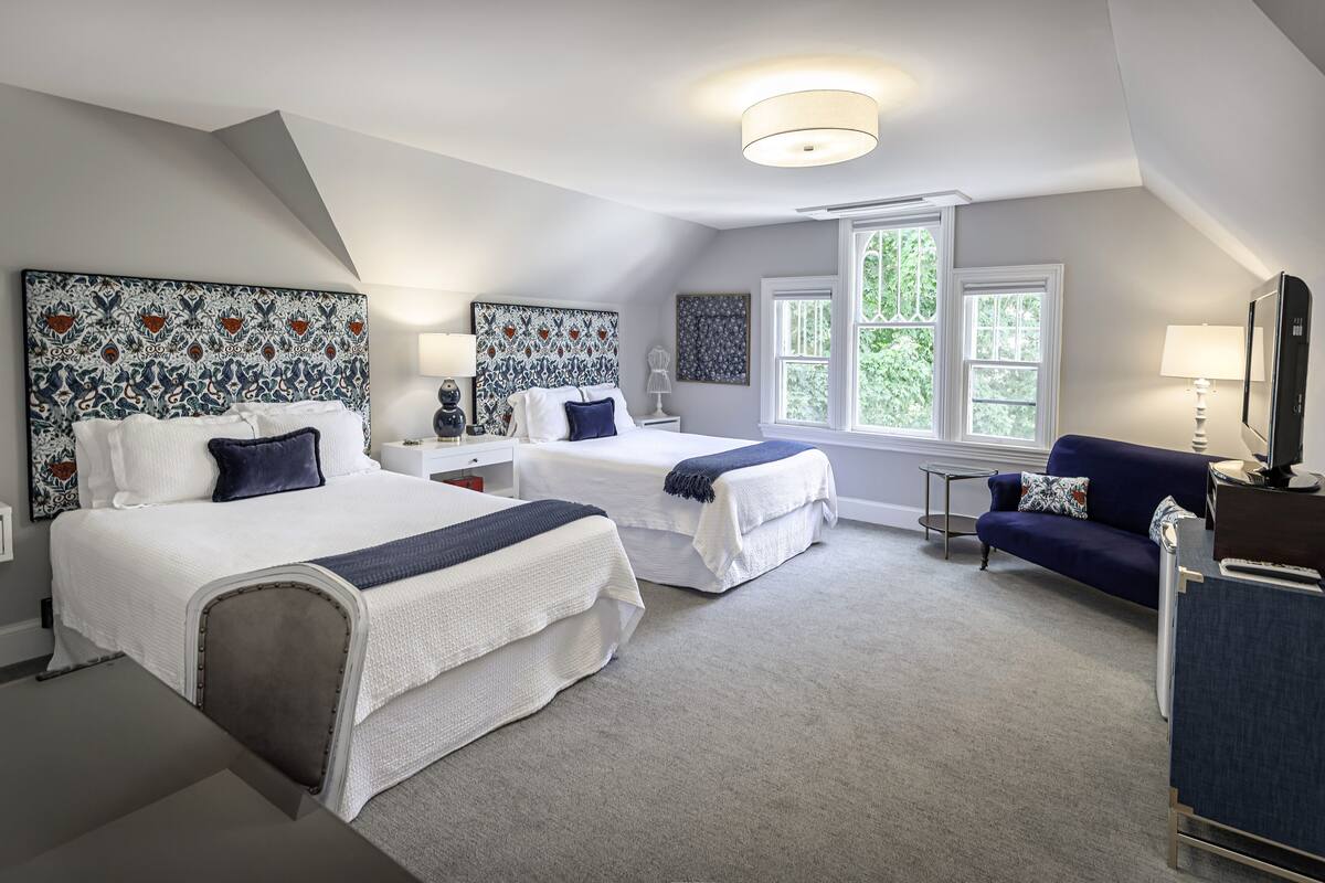 A bedroom with two beds, a sofa, and a desk.