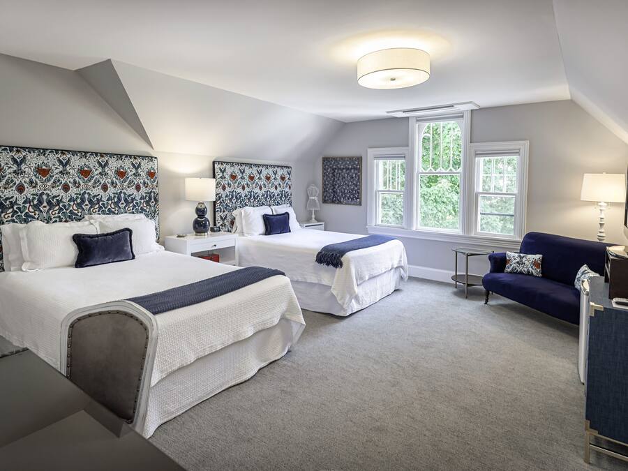 A bedroom with two beds, a sofa, and a desk.