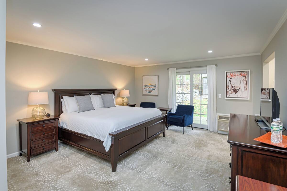 A bedroom with a large bed, bedside tables with lamps, a desk, and chairs.