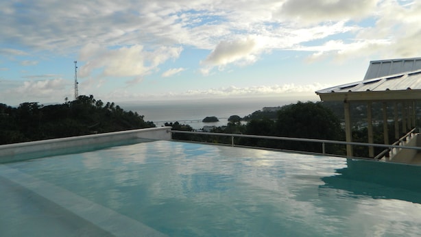 A swimming pool with a view of the ocean and a distant bridge. - Figaro Hotel Boutique (Samaná)