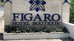 A sign for Figaro Hotel Boutique with a logo and silhouettes of a person playing basketball. - Figaro Hotel Boutique (Samaná)