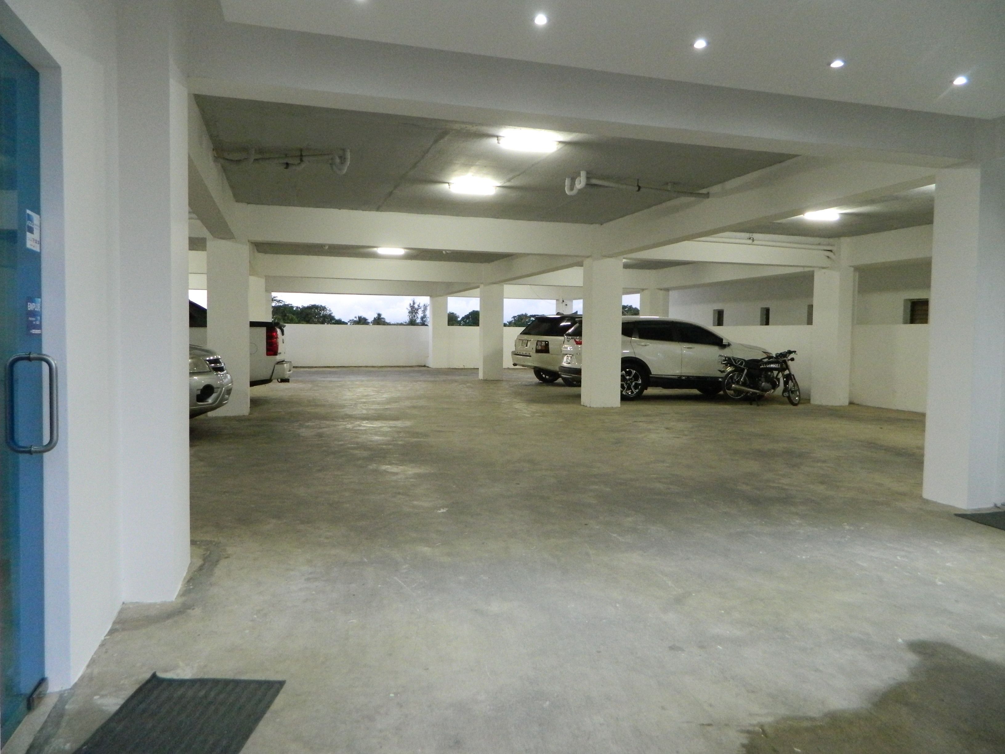 Un parking à plusieurs niveaux, avec des planchers en béton et des murs blancs.